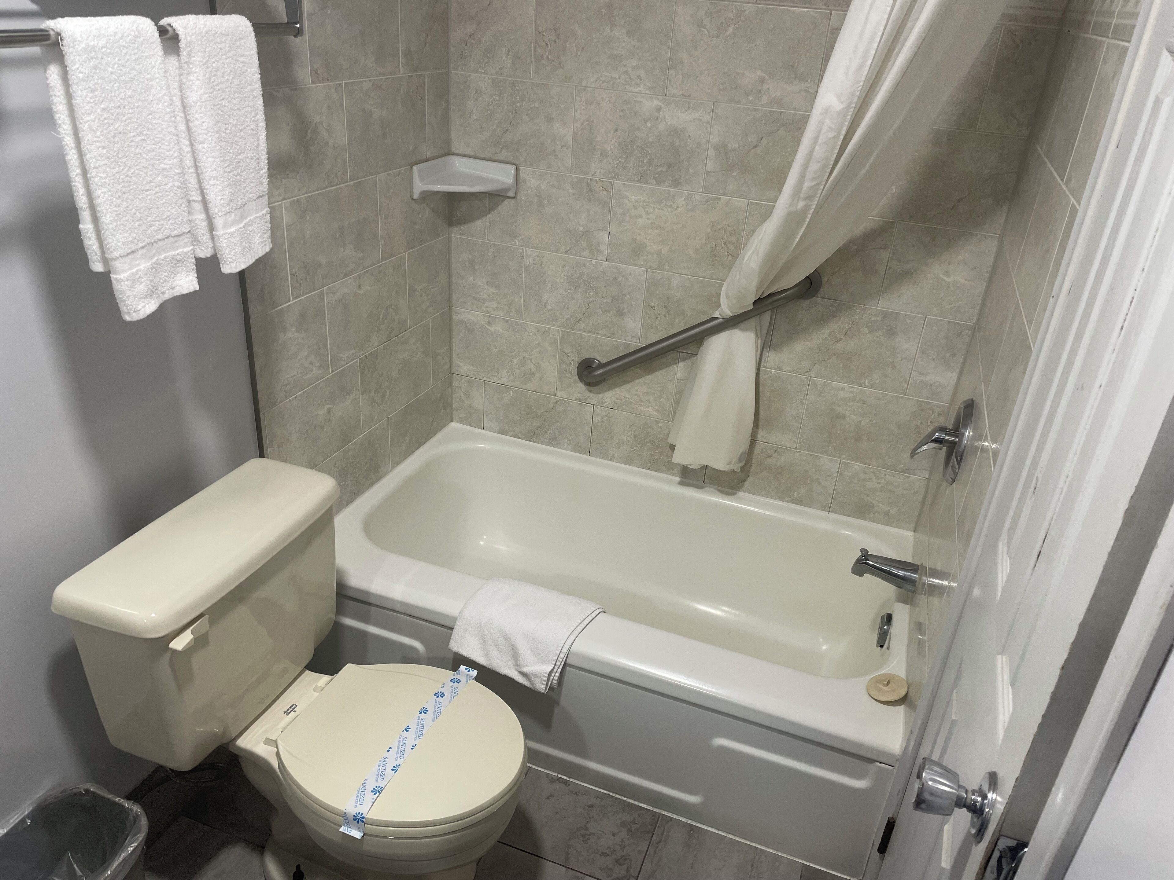 Et badeværelse med toilet, badekar og bruseniche.