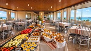 A buffet setup with various food items and a view of the ocean. - Xenius Hotel (João Pessoa)