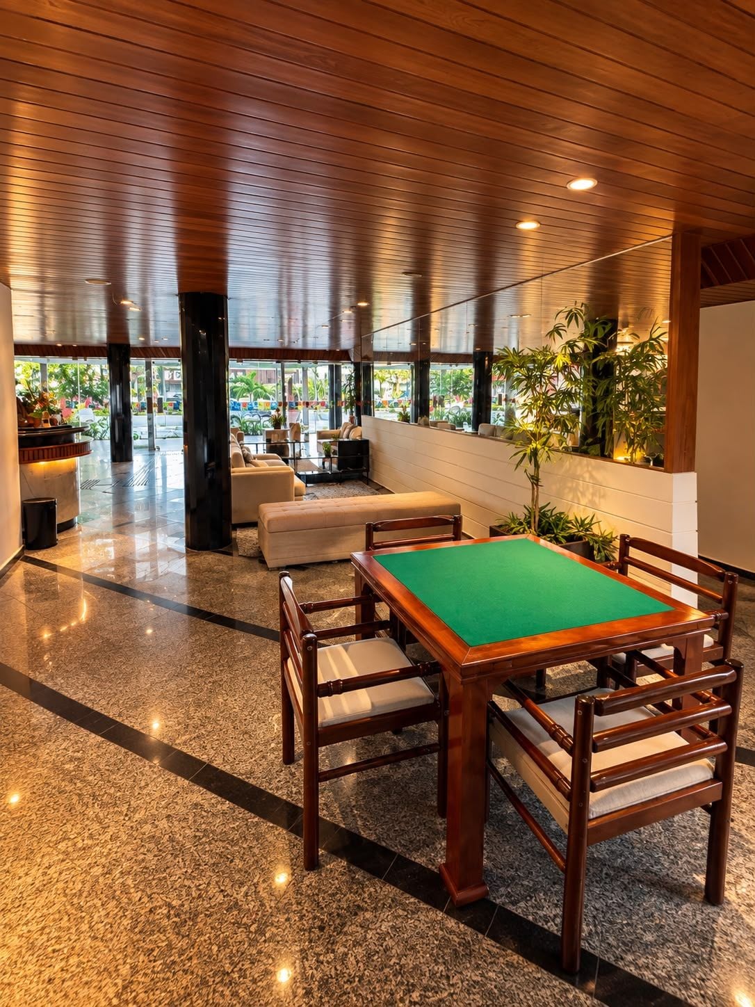 A billiards table with chairs, a sofa, and a coffee table in a room with a wooden ceiling and large windows.