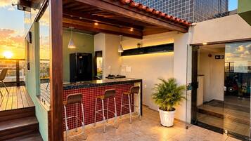 Ein moderner Außenbereich mit Küchenzeile, Bar, Sitzgelegenheiten und einem Blumentopf.