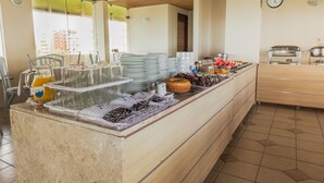 A buffet setup with plates, glasses, and food items. - Xenius Hotel (João Pessoa)