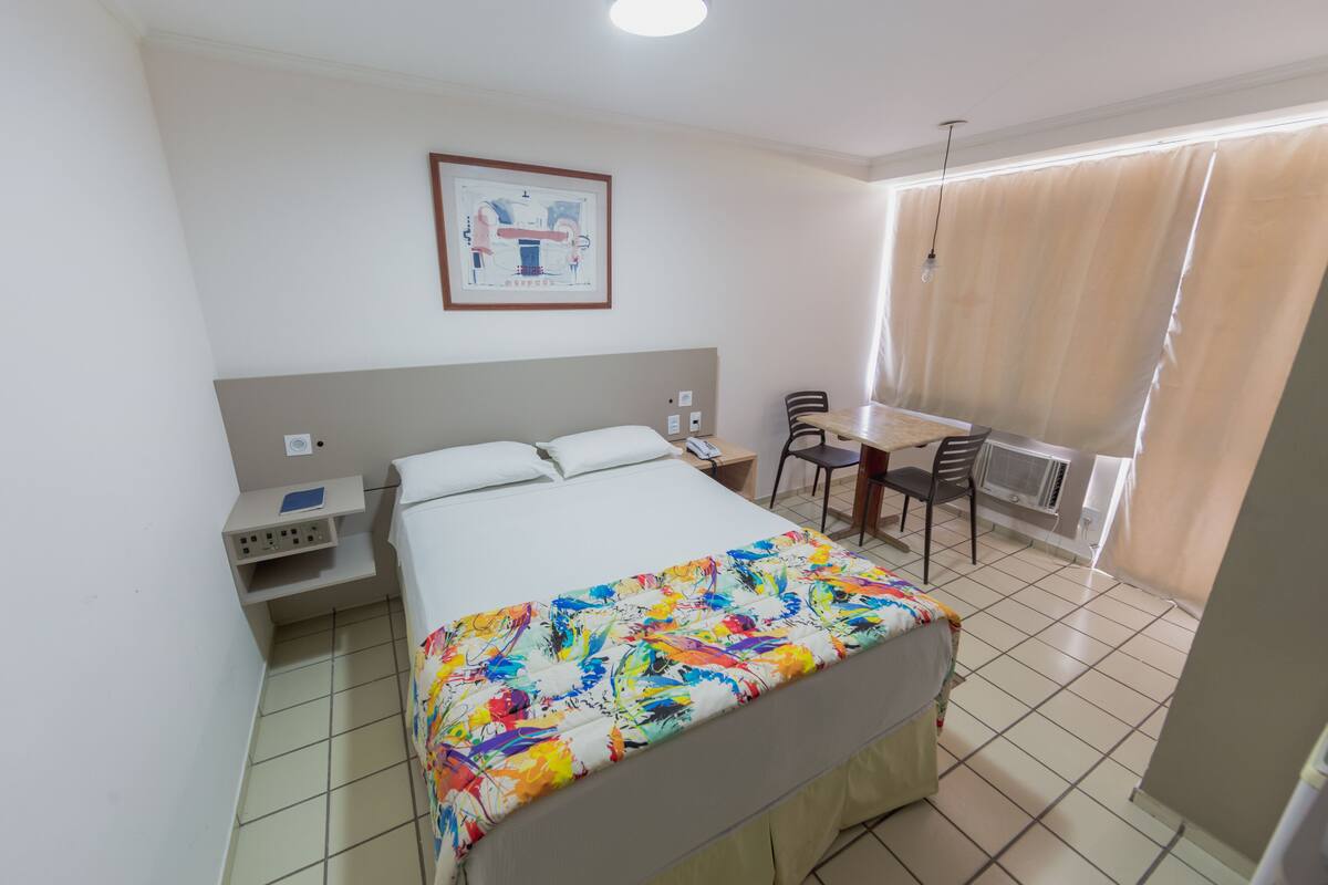 A hotel room with a bed, a desk, and a chair.