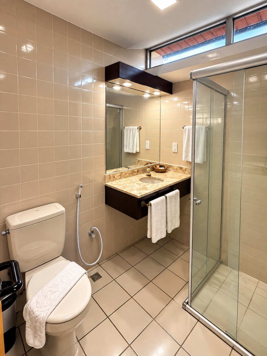 A modern bathroom with a toilet, sink, and glass-enclosed shower.