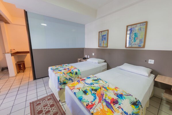 Een hotelkamer met twee bedden, een klein tafeltje en een stoel. Er is een raam en een schilderij aan de muur.