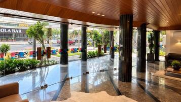 A modern lobby with a wooden ceiling, a glass entrance, and a seating area with a white rug.
