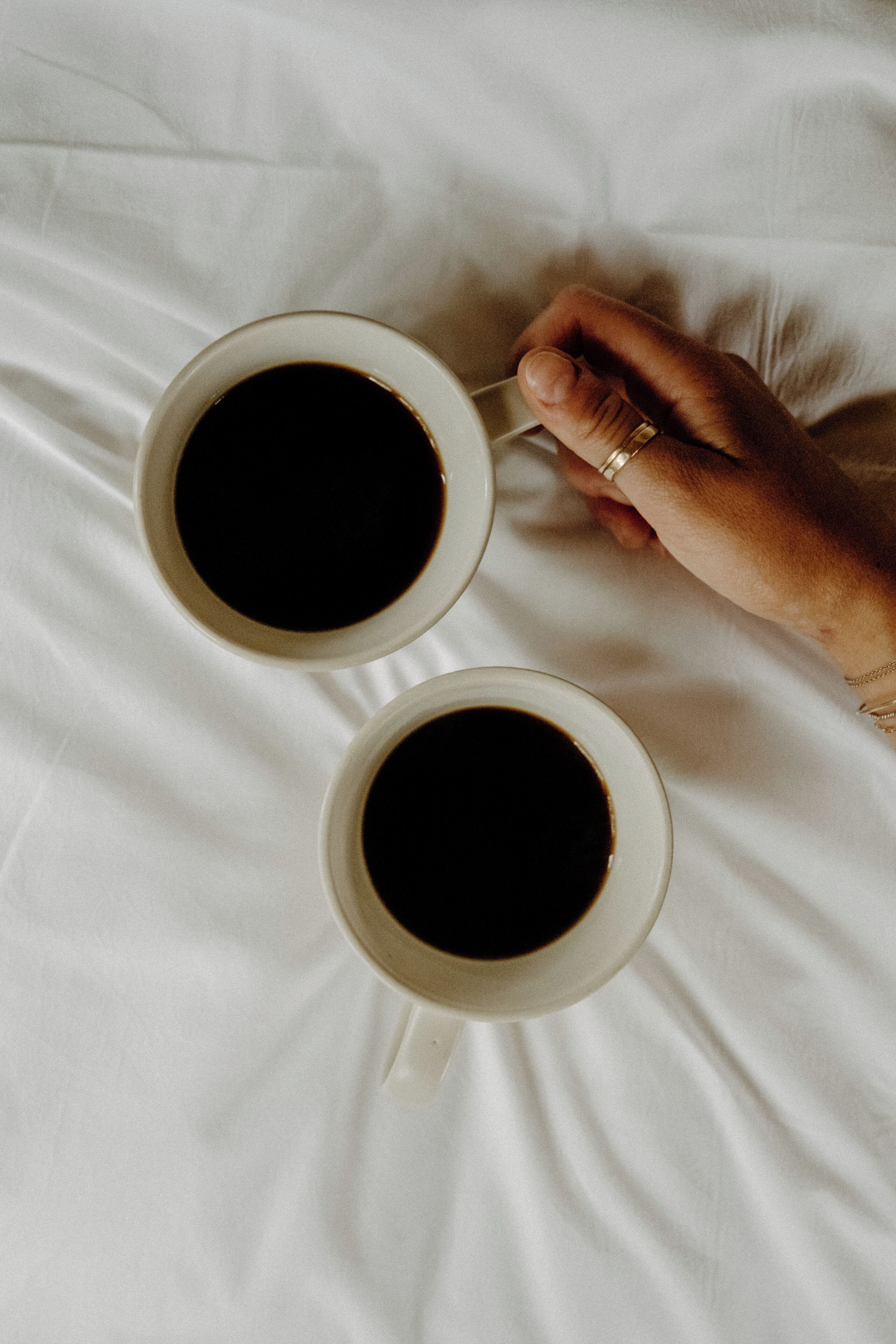 To hvide kaffekopper på et hvidt lagen.