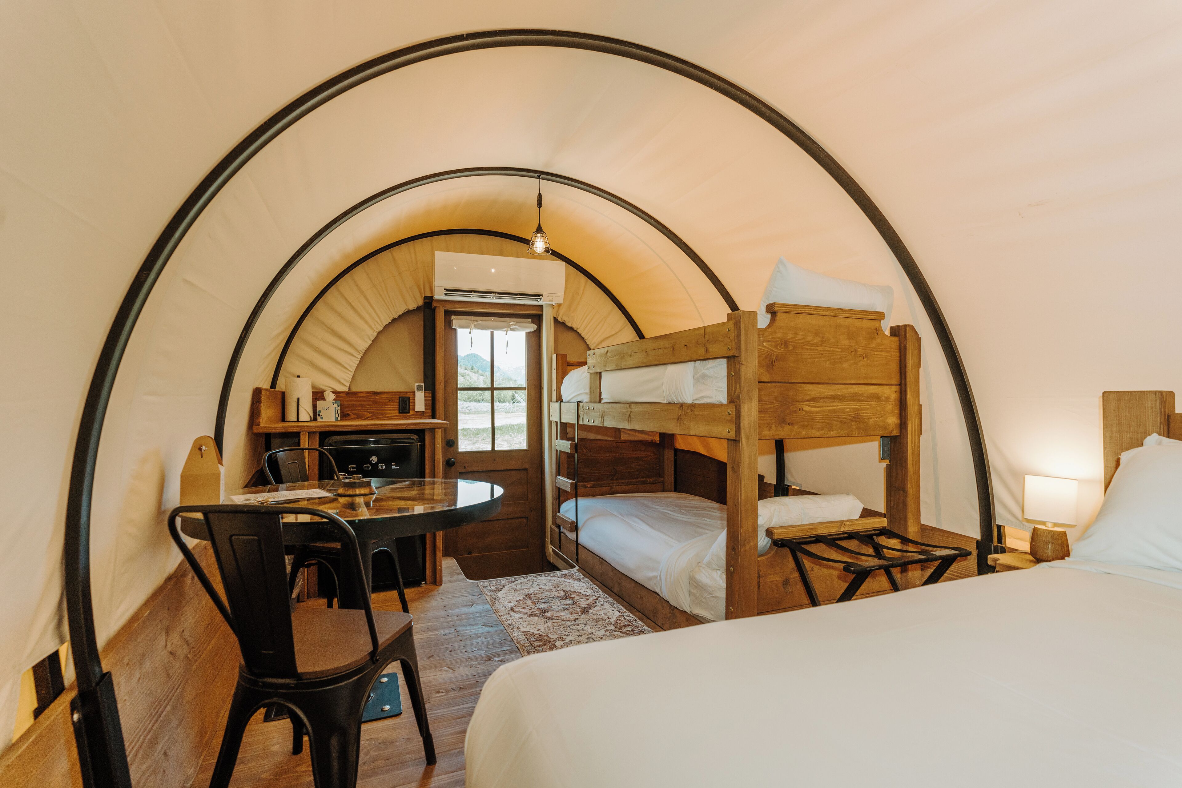 Een tentaccomodatie met stapelbedden, een eethoek en een kitchenette.