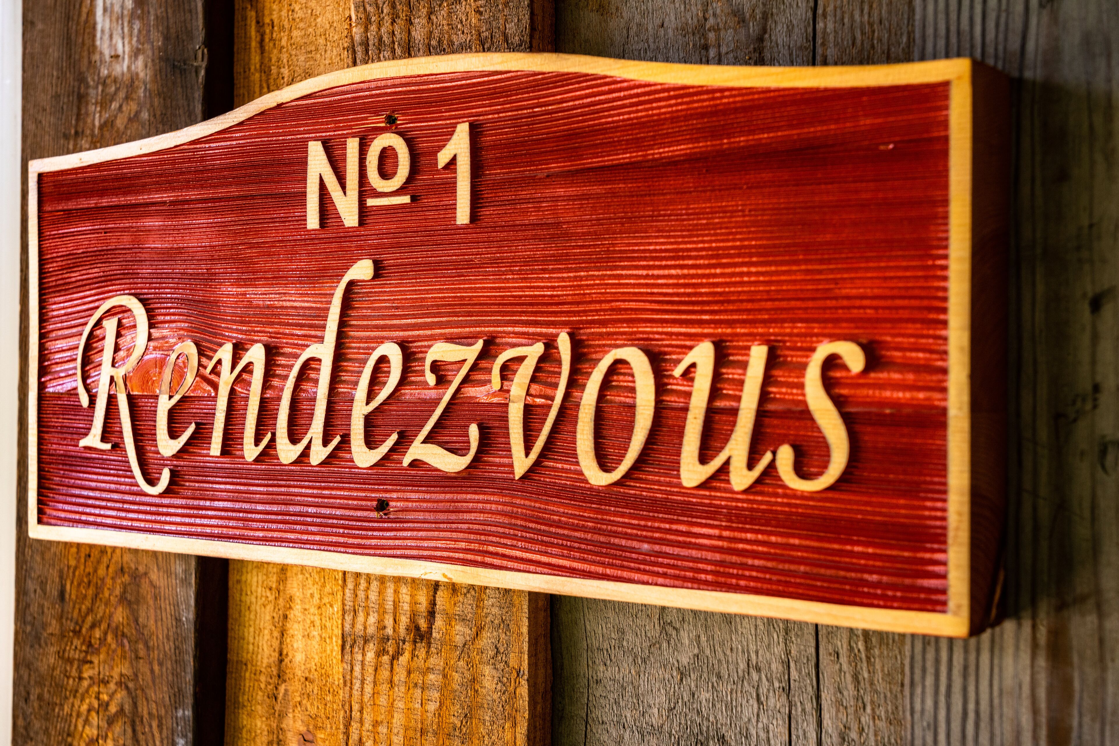 A wooden sign with the text "No 1 Randezvous" mounted on a wooden background.