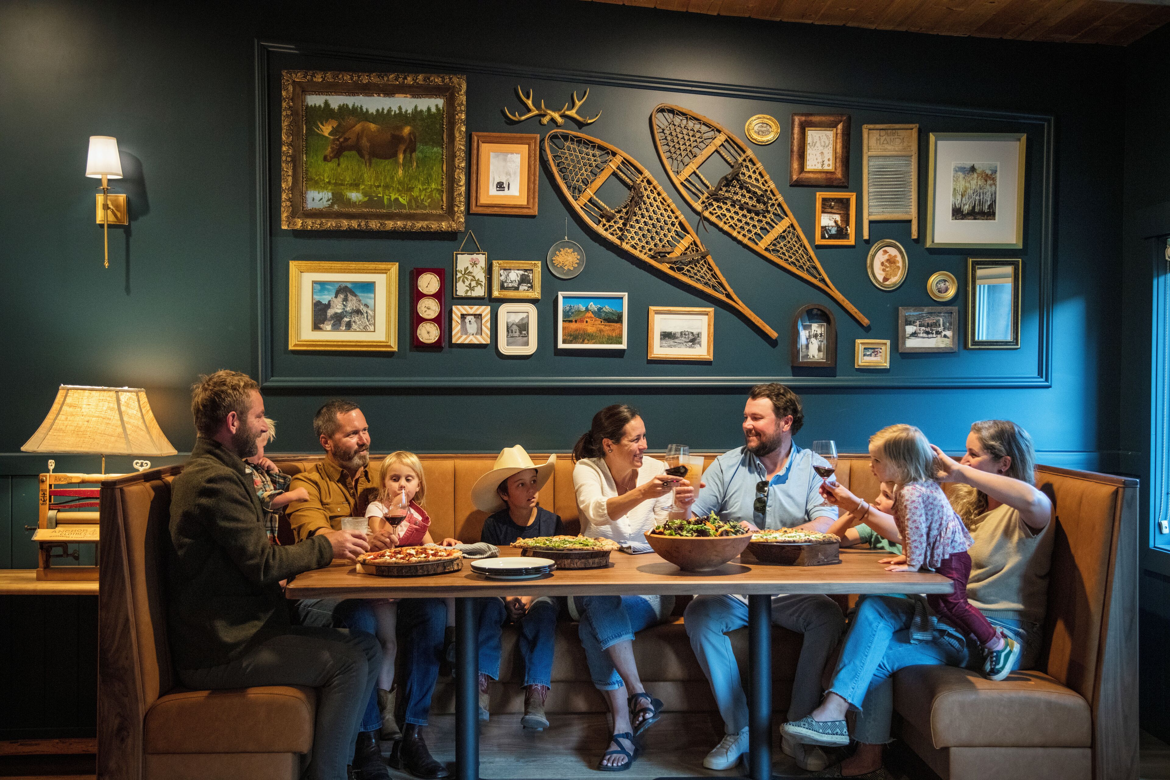A family dining at a restaurant with a wall decorated with framed pictures and a canoe.