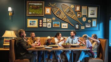 A family dining at a restaurant with a wall decorated with framed pictures and a canoe.