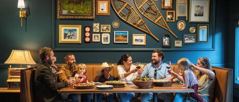 A family dining at a restaurant with a wall decorated with framed pictures and a canoe.