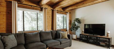 A modern living room with a sectional sofa, a flat-screen TV, and a wooden ceiling.