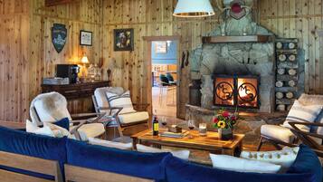 A cozy lodge interior with a stone fireplace, wooden walls, and comfortable seating.