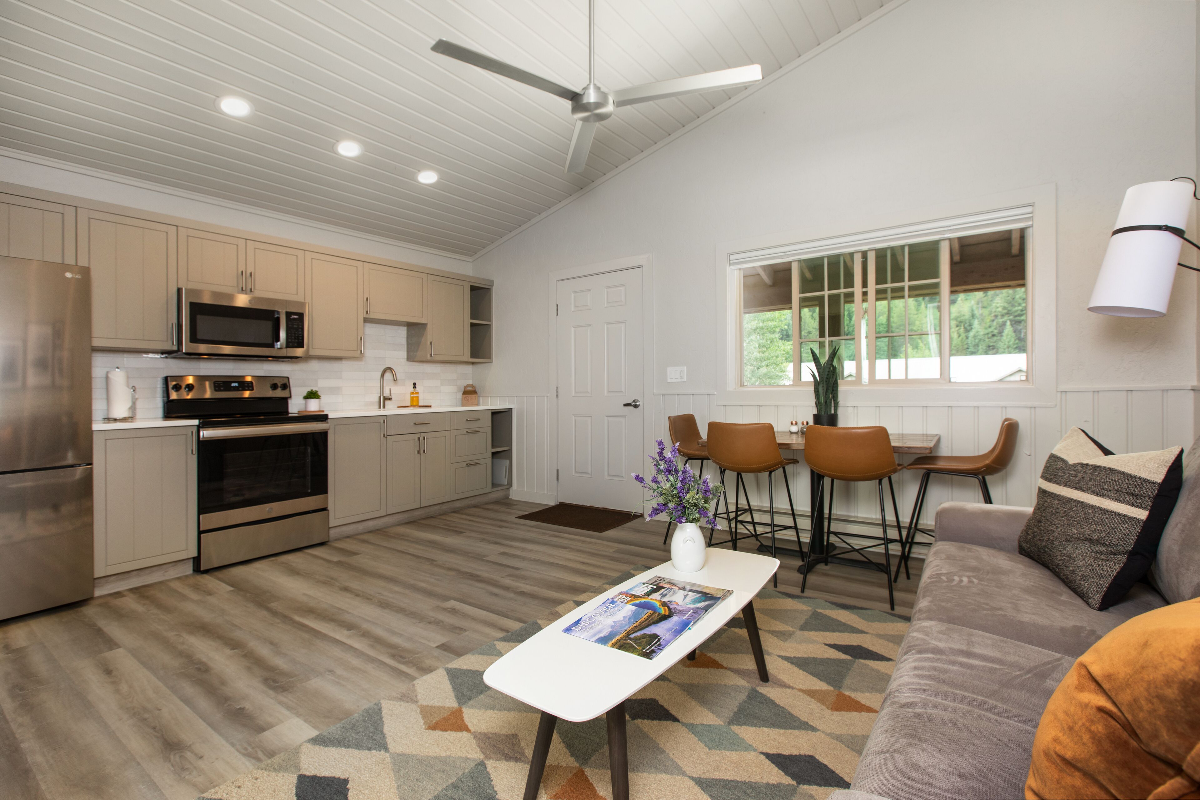 Una cocina moderna con electrodomésticos de acero inoxidable, un comedor con mesa y sillas, y una sala de estar con sofá y mesa de centro.