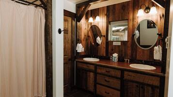 Un baño de madera con dos lavamanos, un espejo grande y una cortina de ducha.