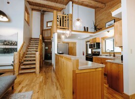 A spacious kitchen with wooden cabinets, a central island, and a view of a lake through the window.