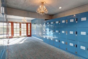 A hallway with blue lockers, a chandelier, and patterned carpet. - Tradewinds All Suite Hotel (Inglewood)