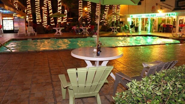 Un espace aménagé au bord de la piscine, avec une table et des chaises, entouré d’une terrasse carrelée.