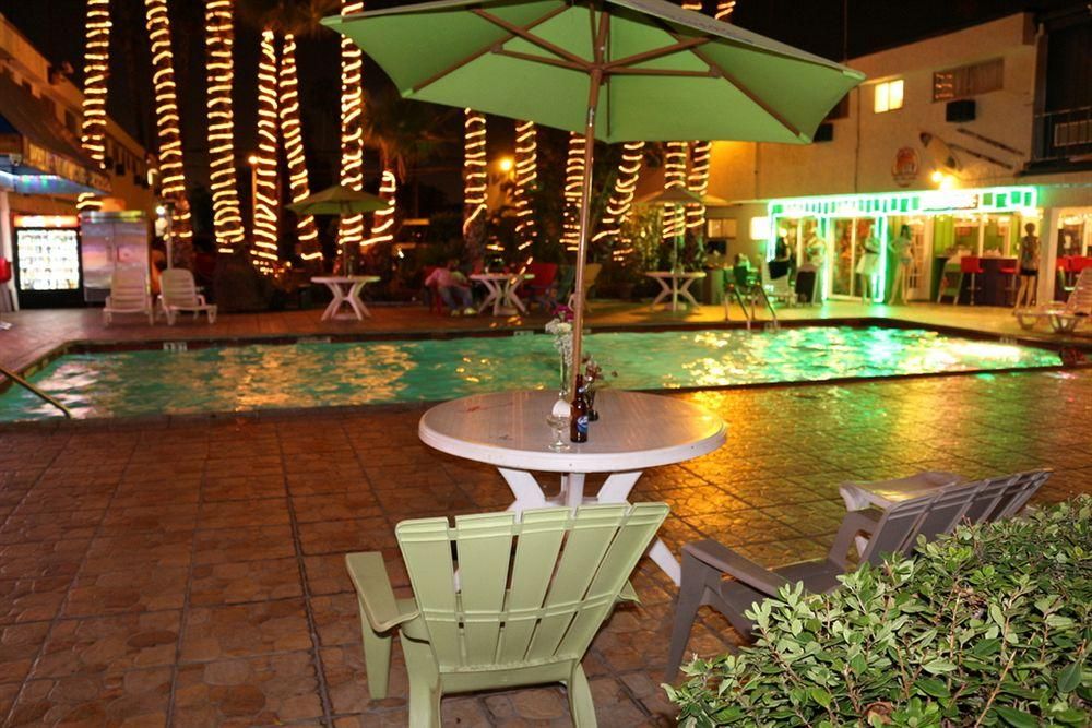 A poolside area with a table and chairs, surrounded by a tiled patio.