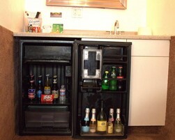 Un refrigerador pequeño con bebidas y un microondas encima.