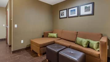 A modern living room with a sectional sofa, a matching ottoman, and a wall with framed pictures.