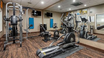 Une salle de sport équipée de machines de cardio, de matériel de musculation et dotée d’un mur avec des miroirs.
