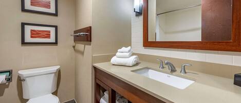 A bathroom with a toilet, sink, and mirror. There are two framed pictures on the wall.