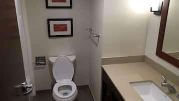 A bathroom with a toilet, sink, and two framed pictures on the wall.
