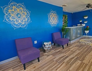 A reception area with blue walls, two purple chairs, a reception desk, and a decorative plant.