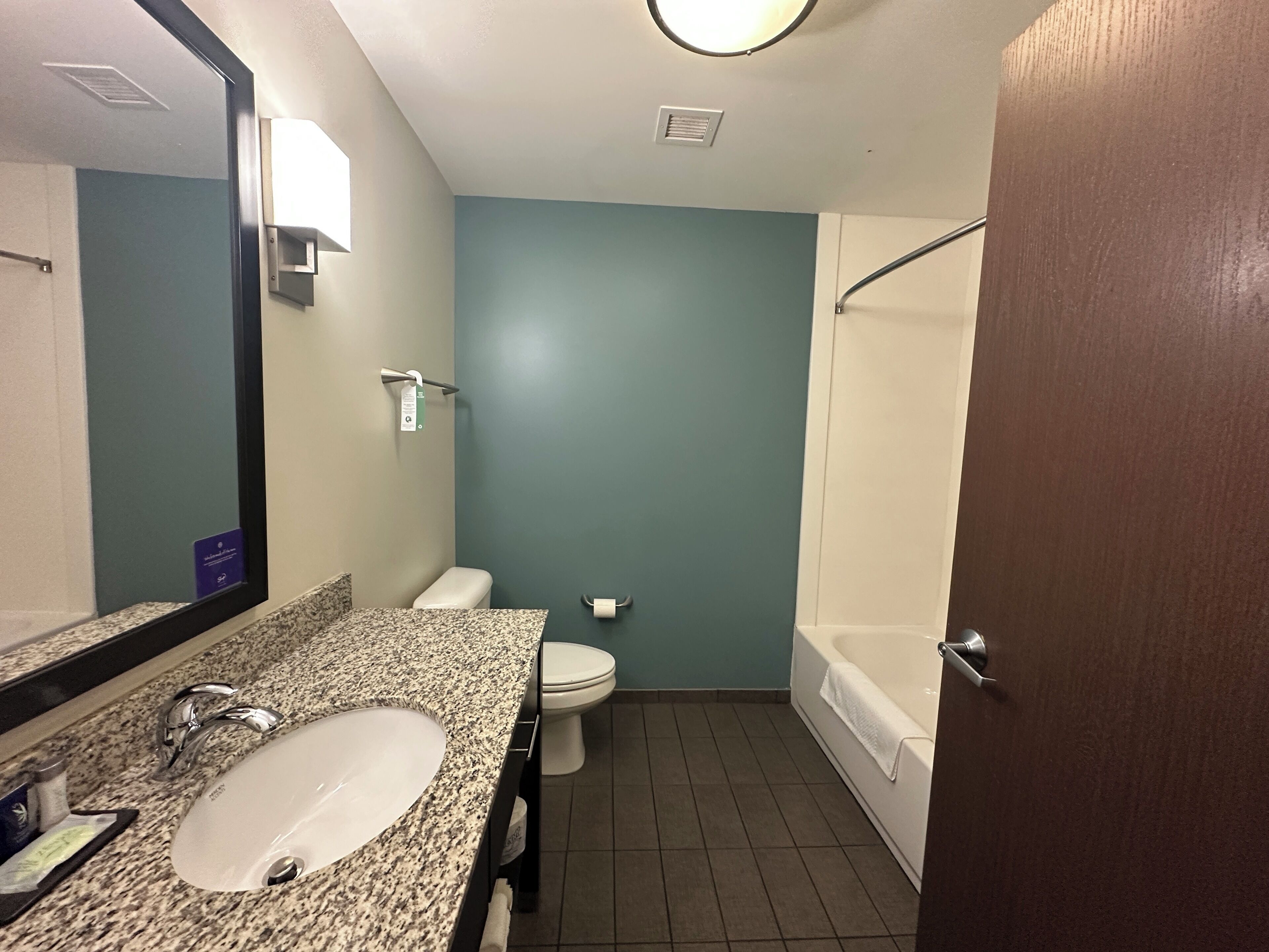 A bathroom with a granite countertop sink, a toilet, and a bathtub.