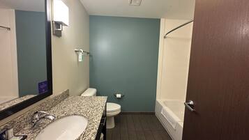 A bathroom with a granite countertop sink, a toilet, and a bathtub.