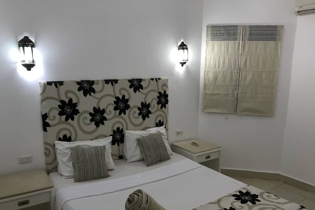 A neatly made bed with a floral headboard, bedside tables, and wall-mounted lights.
