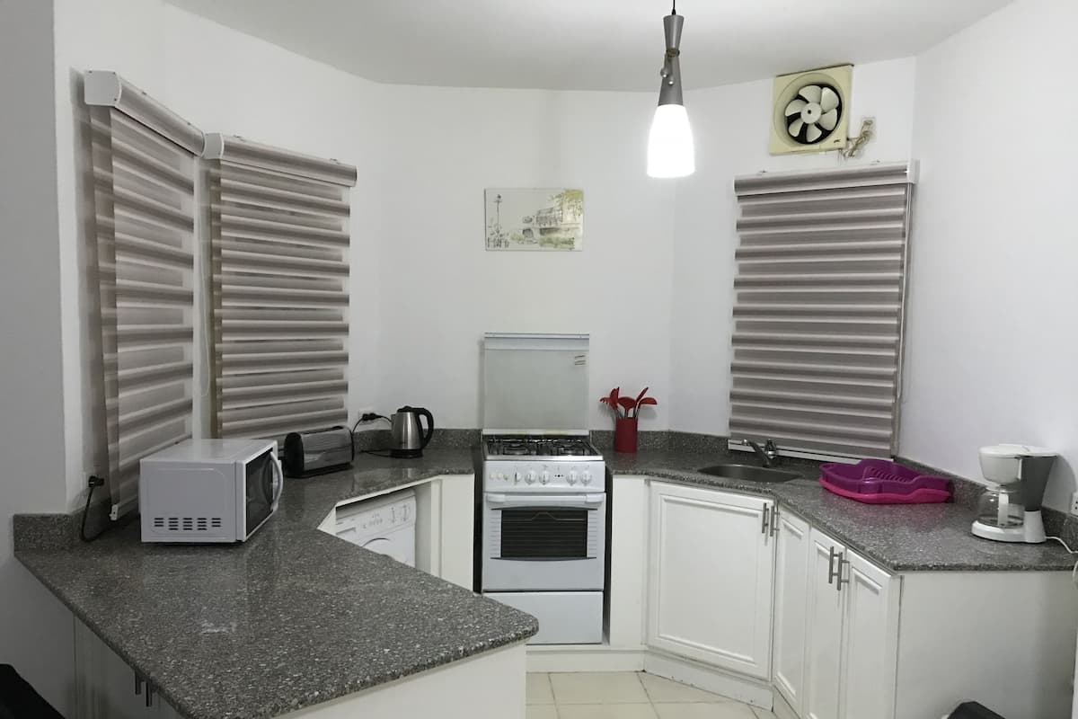A compact kitchen with white cabinets, a gas stove, a microwave, a toaster, and a sink.