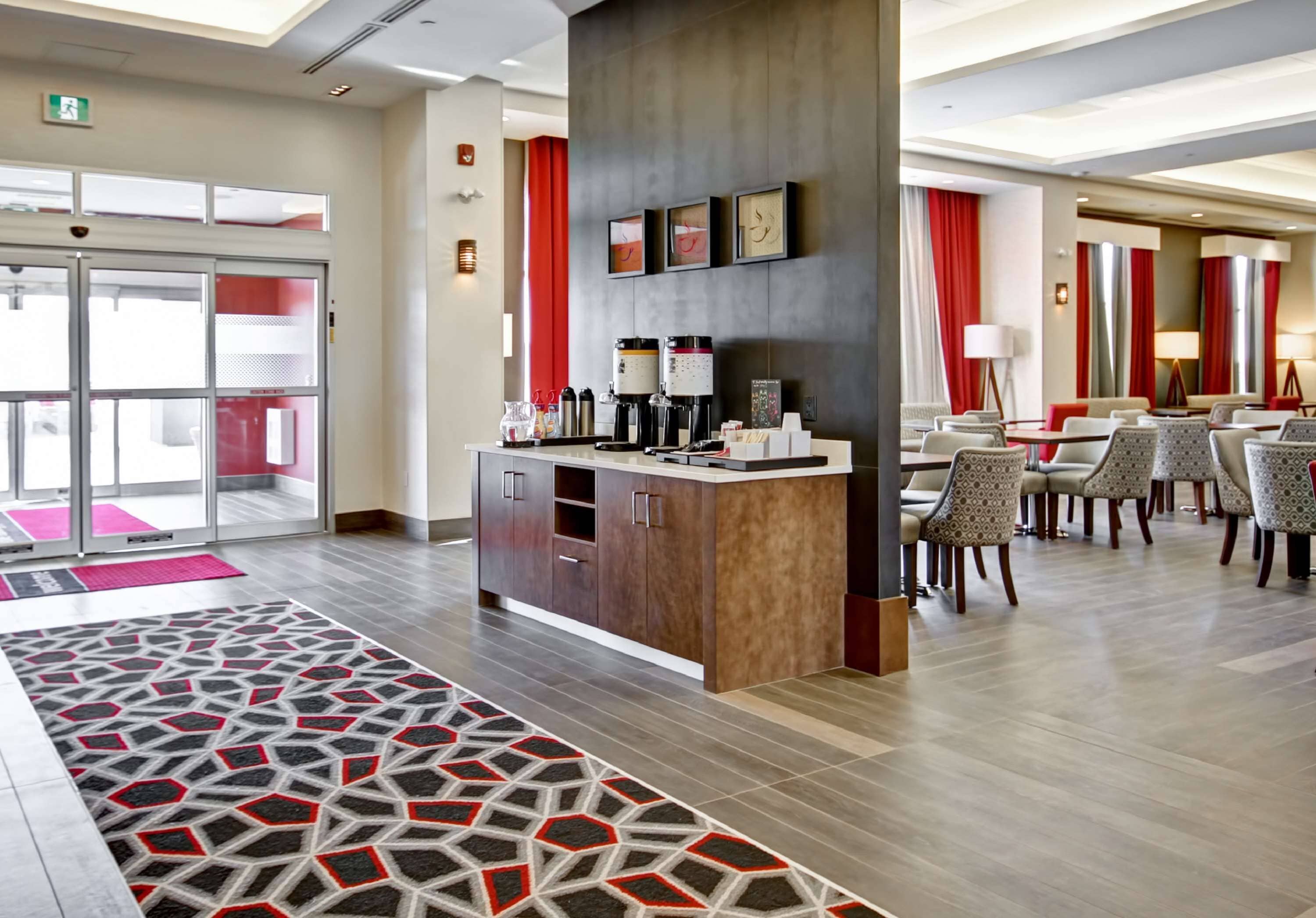 Un moderno vestíbulo de hotel con mostrador de recepción, zona de estar y alfombra estampada.