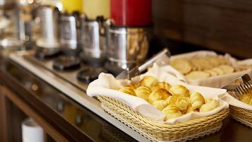 A buffet table with baskets of pastries and condiments.