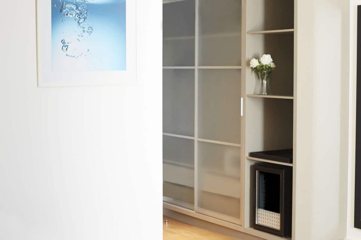 A room with a sliding door closet, a small shelf with a vase of flowers, and a mirror.