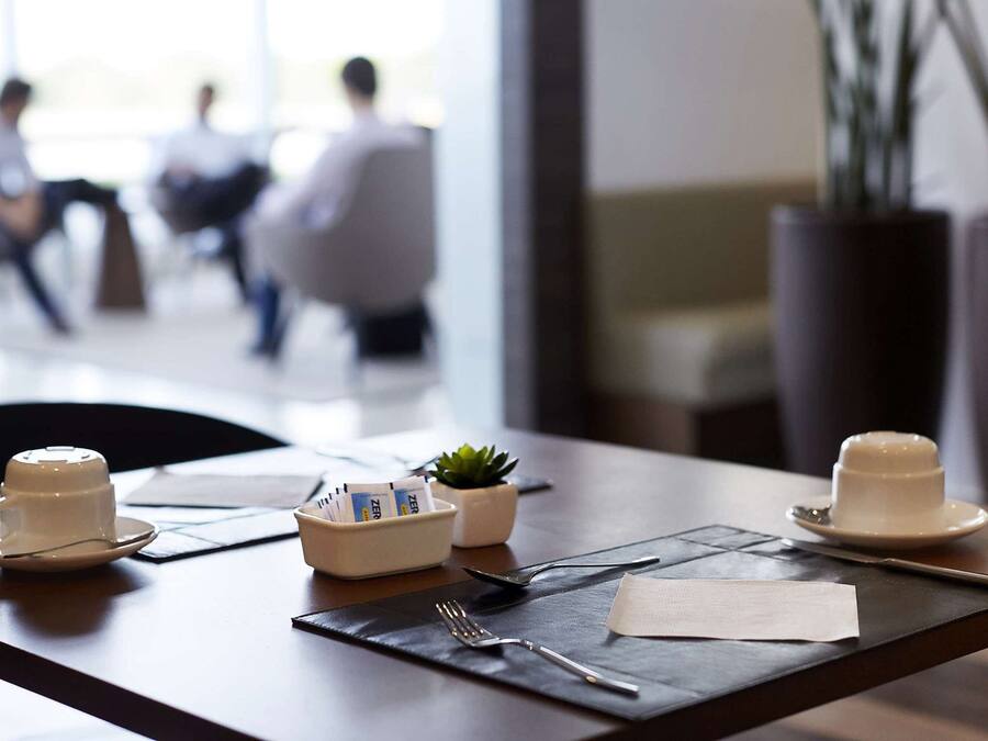 A dining table with a cup, a small plant, a napkin, and a menu.
