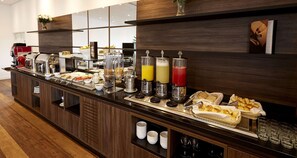 Un mostrador de buffet con diversos alimentos, bebidas y una estación de café.
