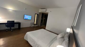 Una camera d'albergo moderna con un letto grande, una scrivania con un computer, una televisione e un condizionatore d'aria.