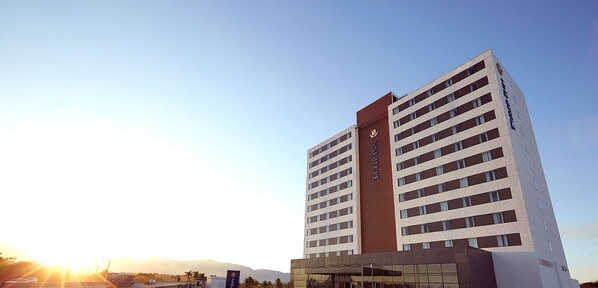 Un hotel alto de diseño moderno, con varios pisos y una entrada destacada.