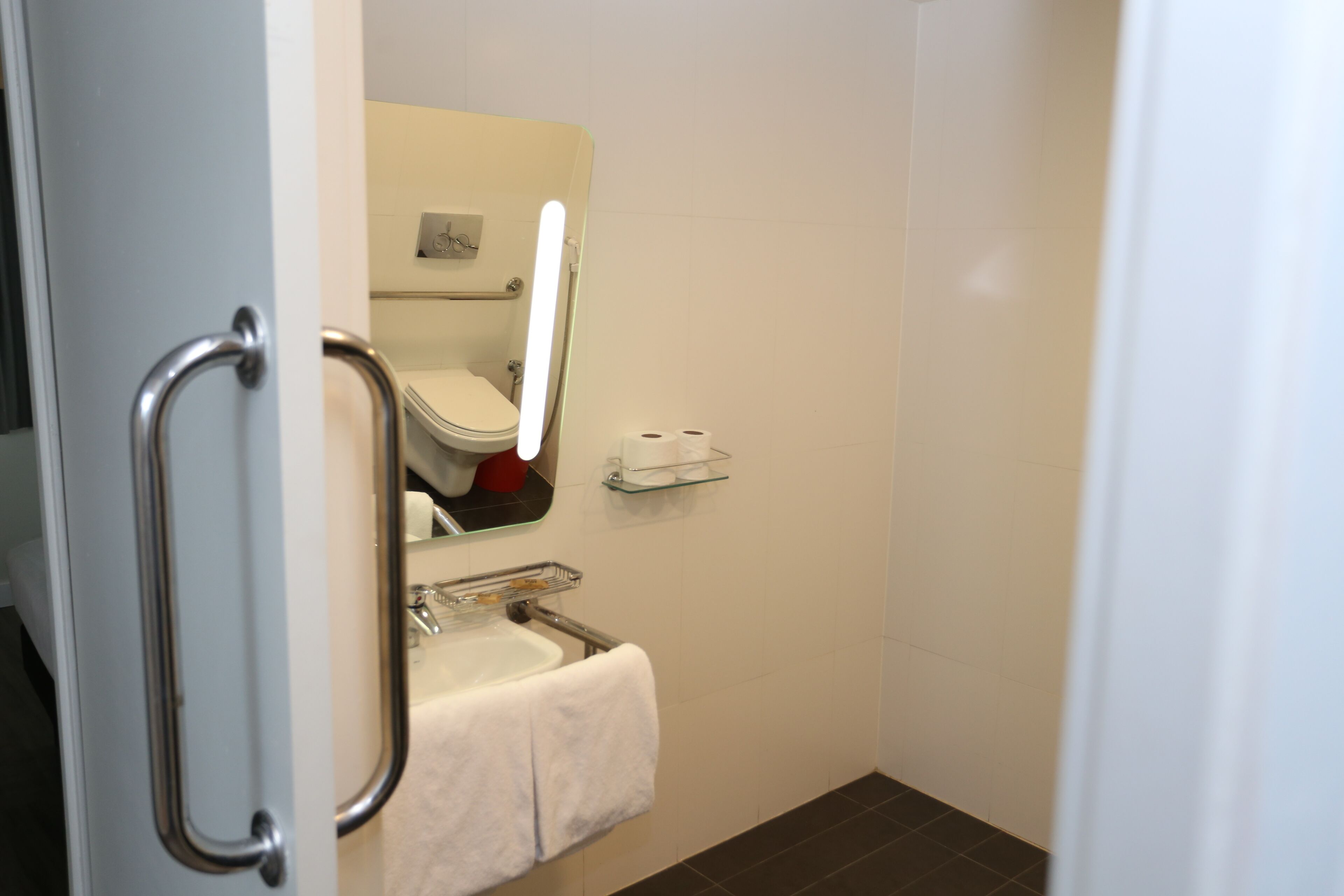Un baño con inodoro, lavamanos y estante de vidrio.