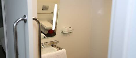 Un baño con inodoro, lavamanos y estante de vidrio.
