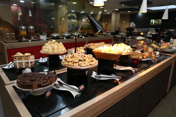 A buffet with various food items including cakes, pastries, and a chocolate cake.