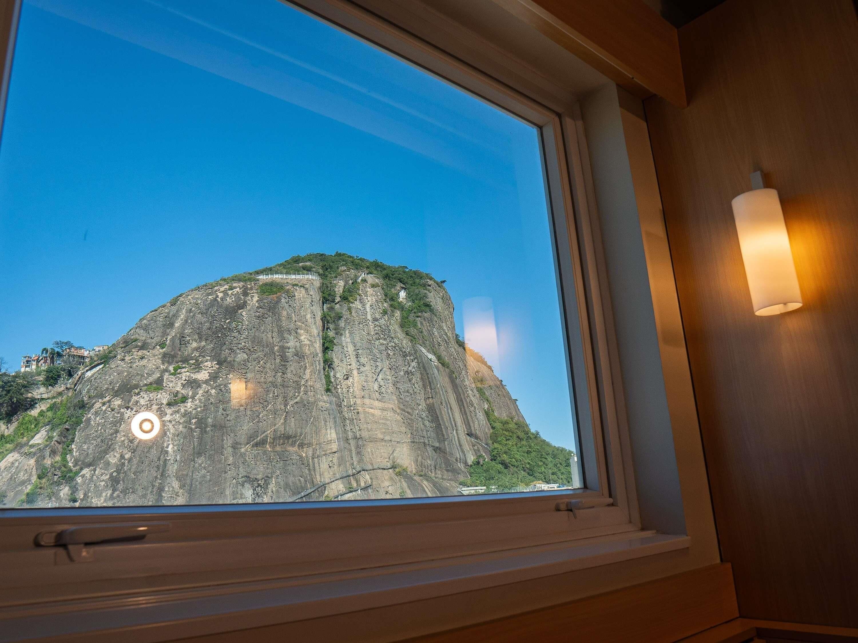 A window with a view of a mountain and a lamp on the wall.