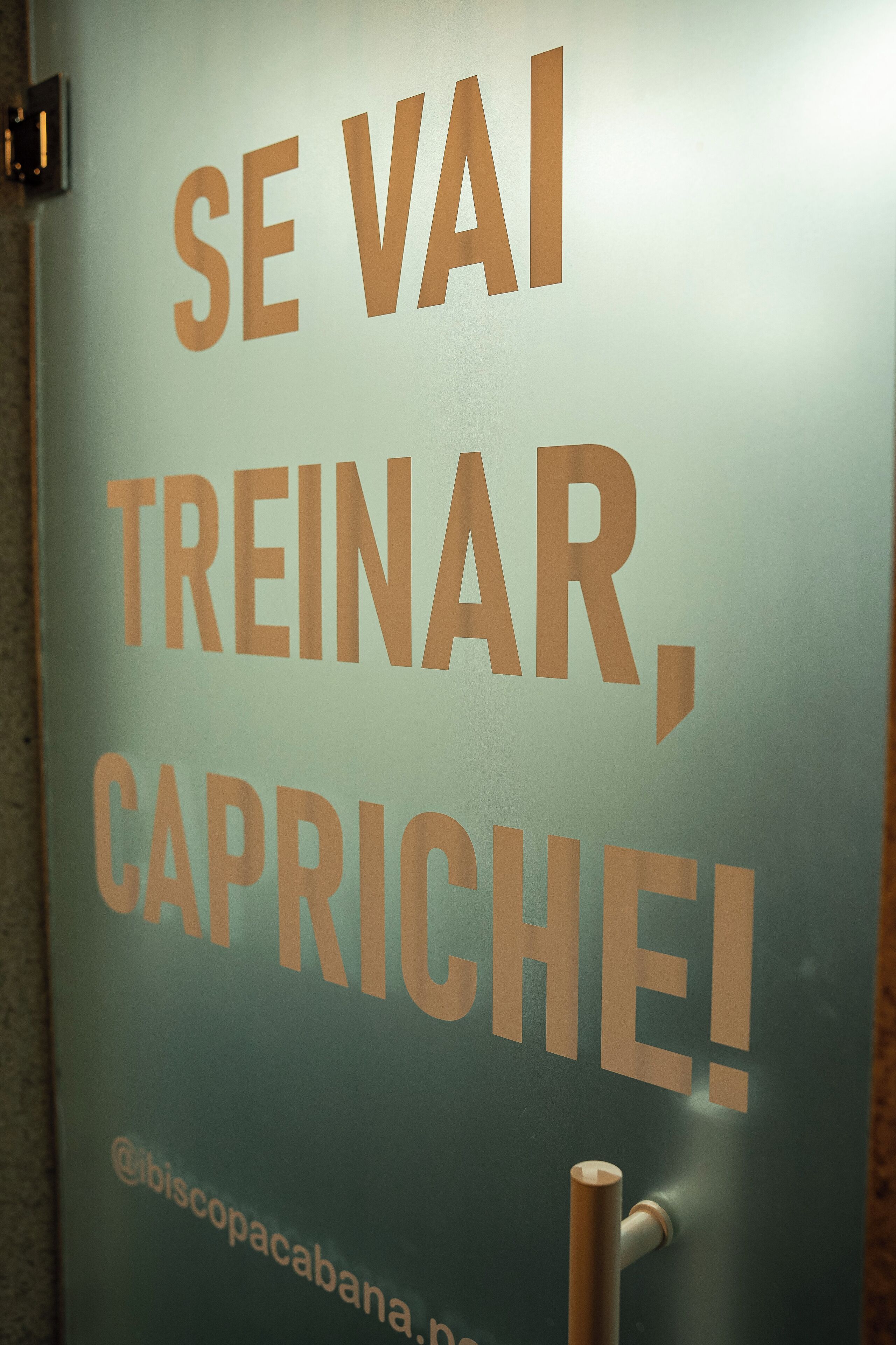 A sign with the text "SE VAI TREINAR, CAPRICHE!" and a handle "@biscopacabana.pn".