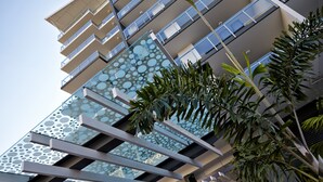 A modern building with multiple balconies and a glass facade with circular patterns. - Verve on Cotton Tree (Maroochydore)