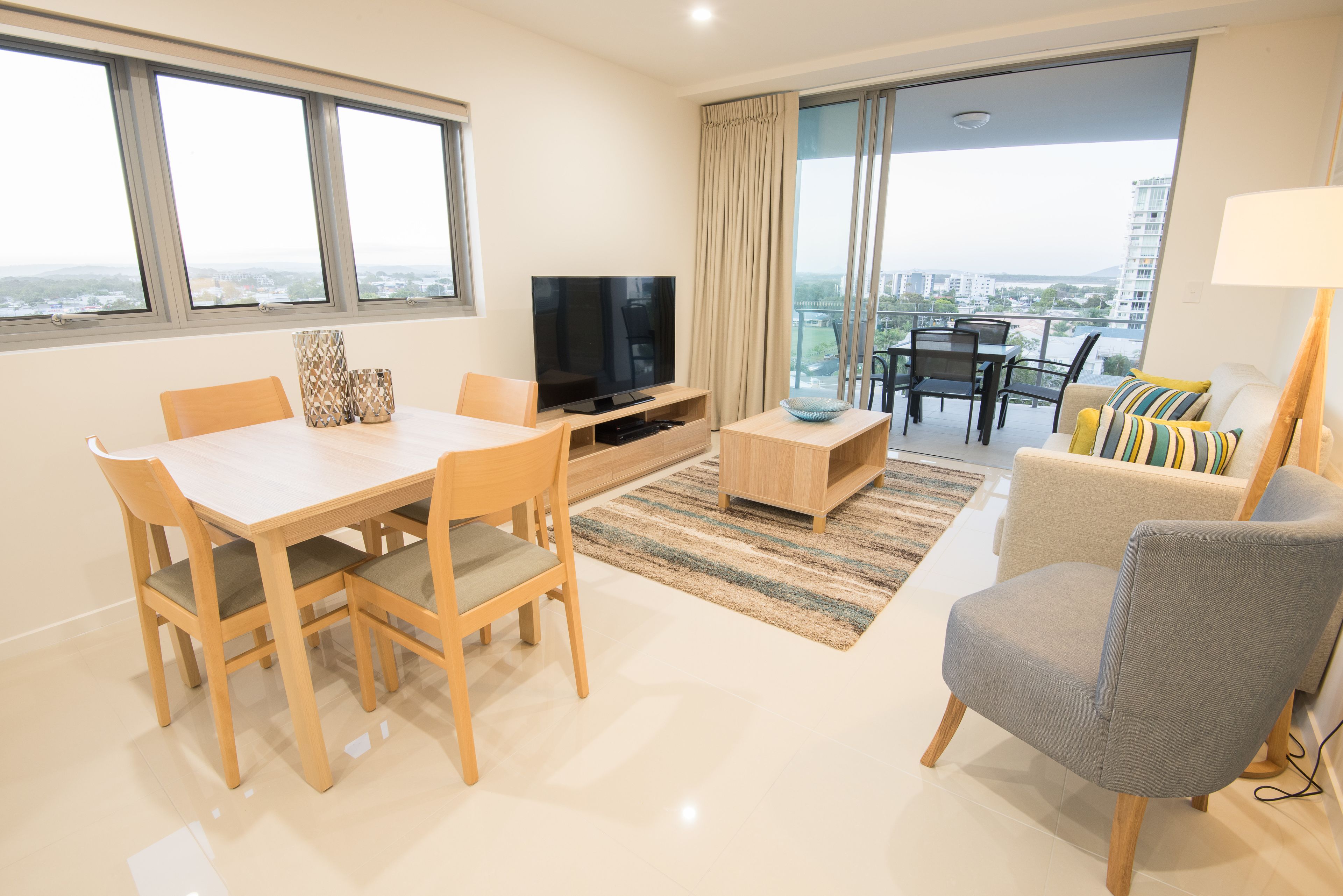 Un salon moderne comprenant une table à manger, des chaises, un téléviseur, un canapé et un balcon avec vue.