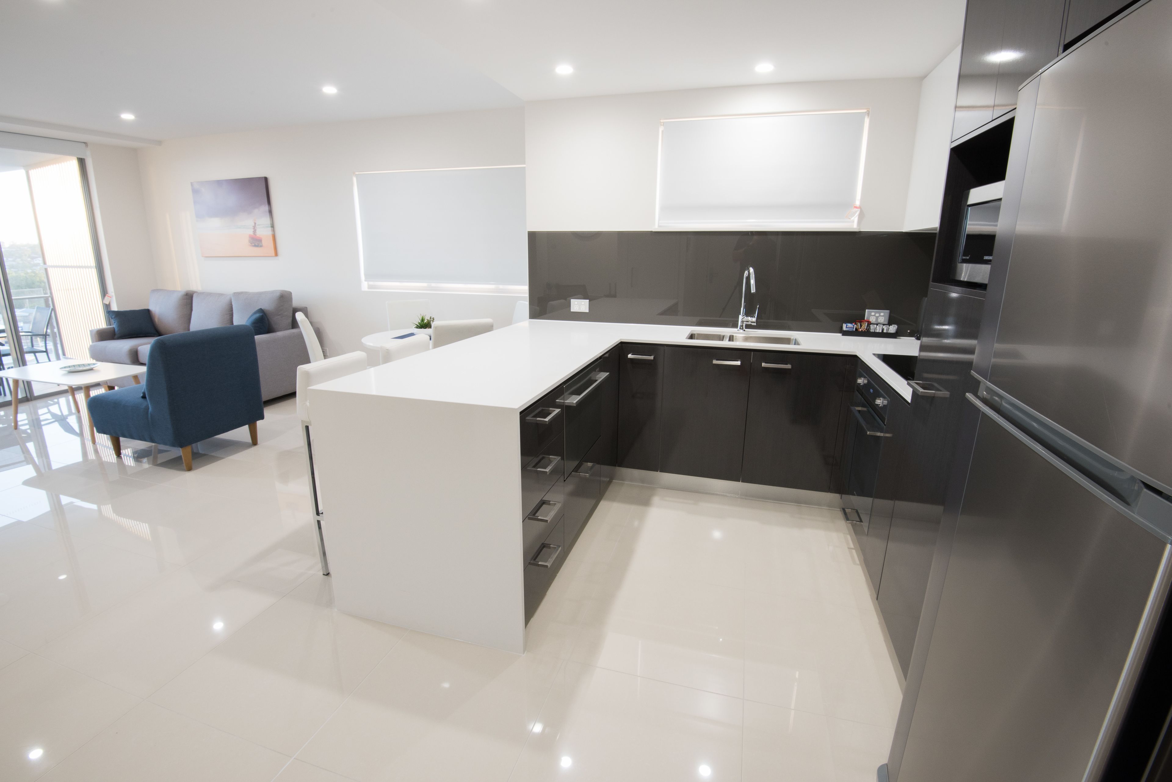 Una cocina moderna con una isla central, muebles oscuros y electrodomésticos de acero inoxidable.
