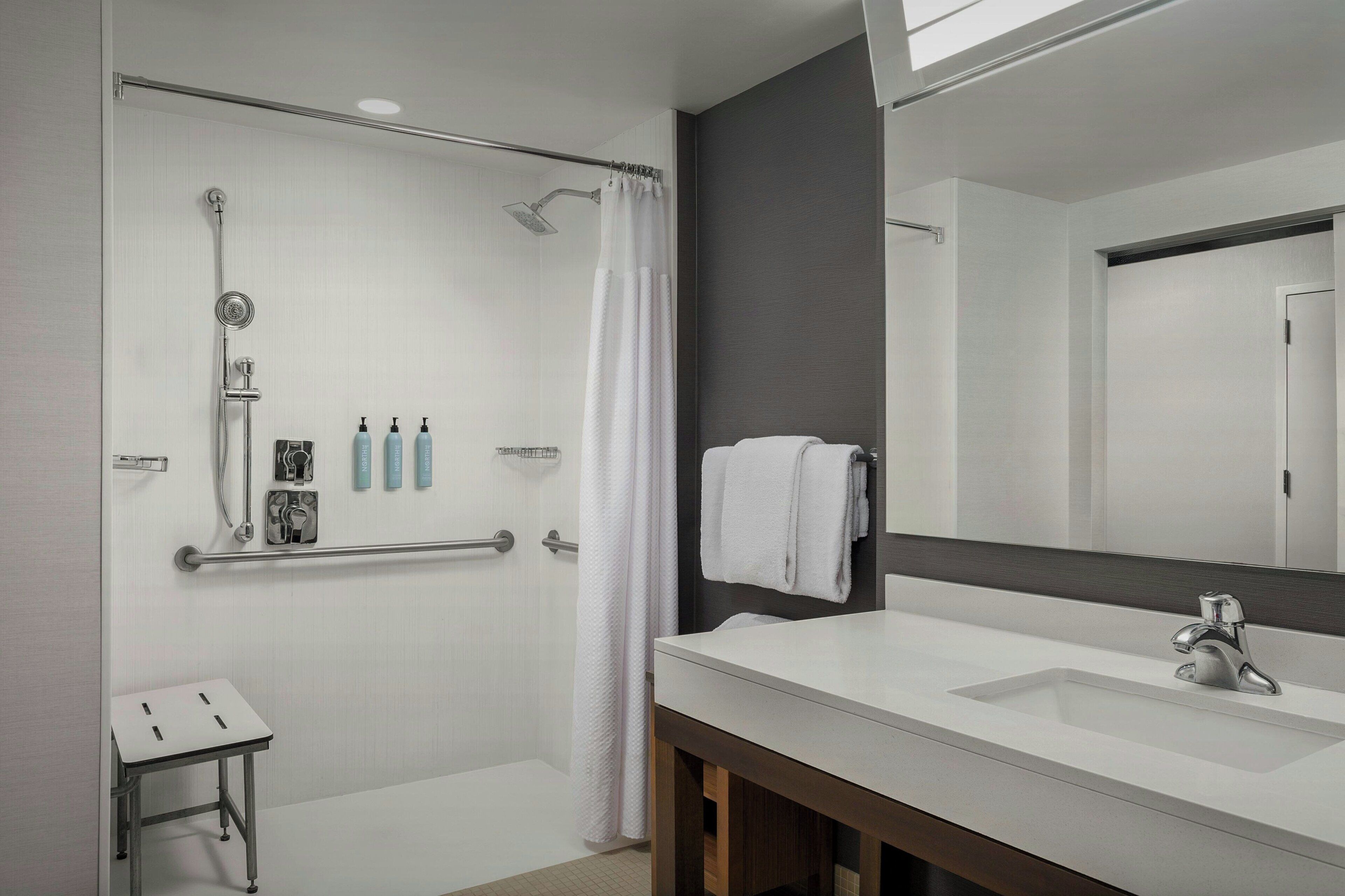 Un baño moderno con ducha, tocador con lavabo y espejo.