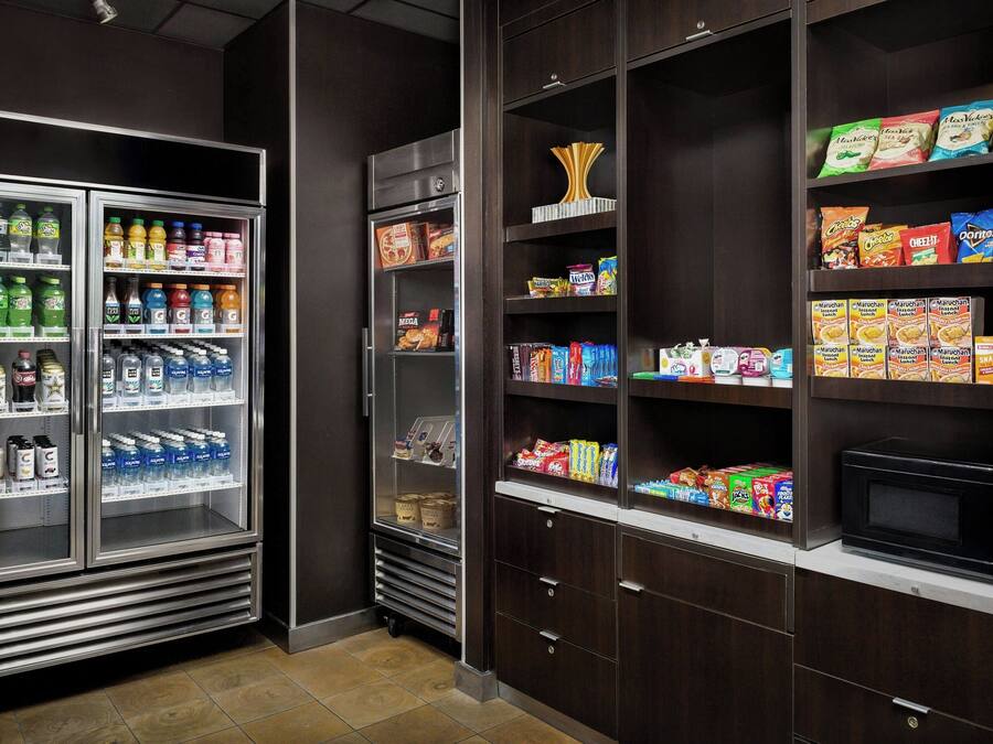 A self-service food station with refrigerated drinks, snacks, and a microwave.